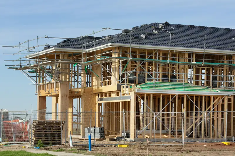 A two-story house in wood framing, wrapped in scaffolding