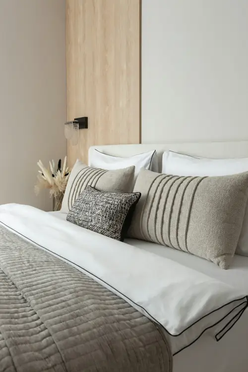 A bed layered in neutral linens and striped pillows