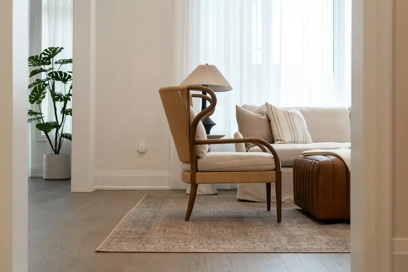 A cream armchair and a leather pouf in a quiet sitting room