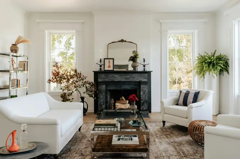 Two white sofas facing a black fireplace in a sunlit living room