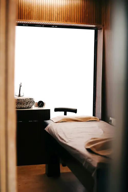 A treatment table dressed in beige linen beside a patterned stone sink
